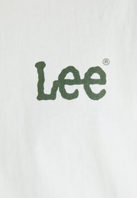 Hvid bomulds t-shirt med et grønt, stiliseret "Lee" logo. Stoffet er glat, med et simpelt, rent design og ingen yderligere grafik.