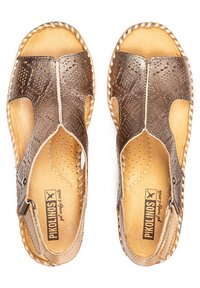 Sandalias de cuero marrón con recortes, detalles de costura y borde trenzado. El interior tiene una textura de cuero natural suave.