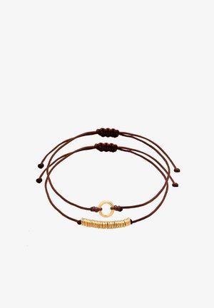 Smeđi narukvica od kord-užeta s dva prilagodljiva strana. Jedan strani ima zlatni okrugli akcenat; drugi ima zlatne spiralne perle.
