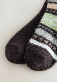 Sötétbarna bolyhos zoknik, zöld, fehér és pasztell csíkokkal díszített mintával; puha tapintás és lekerekített orrdesign.