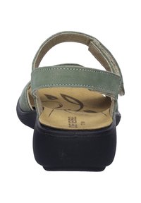 Zelené semišové sandály s černou gumovou podrážkou, s nastavovacími popruhy a tvarovanou stélkou. Vnitřek má design s listovým vzorem.