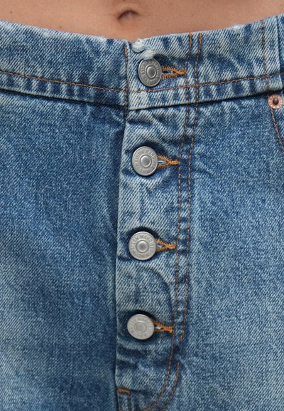 Világoskék mosott hatású farmer szoknya, öt ezüst gombbal, intarziás gravírozással, és narancssárga varrással a varratok mentén.