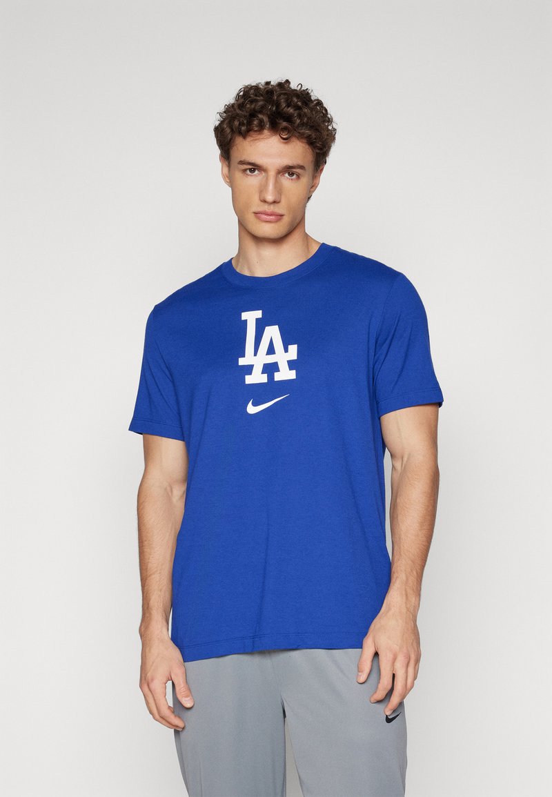Kék pamut póló kerek nyakkal, fehér "LA" logóval és egy kis Nike swoosh-ral. Rövid ujjú és egyenesen vágott aljjal készült.