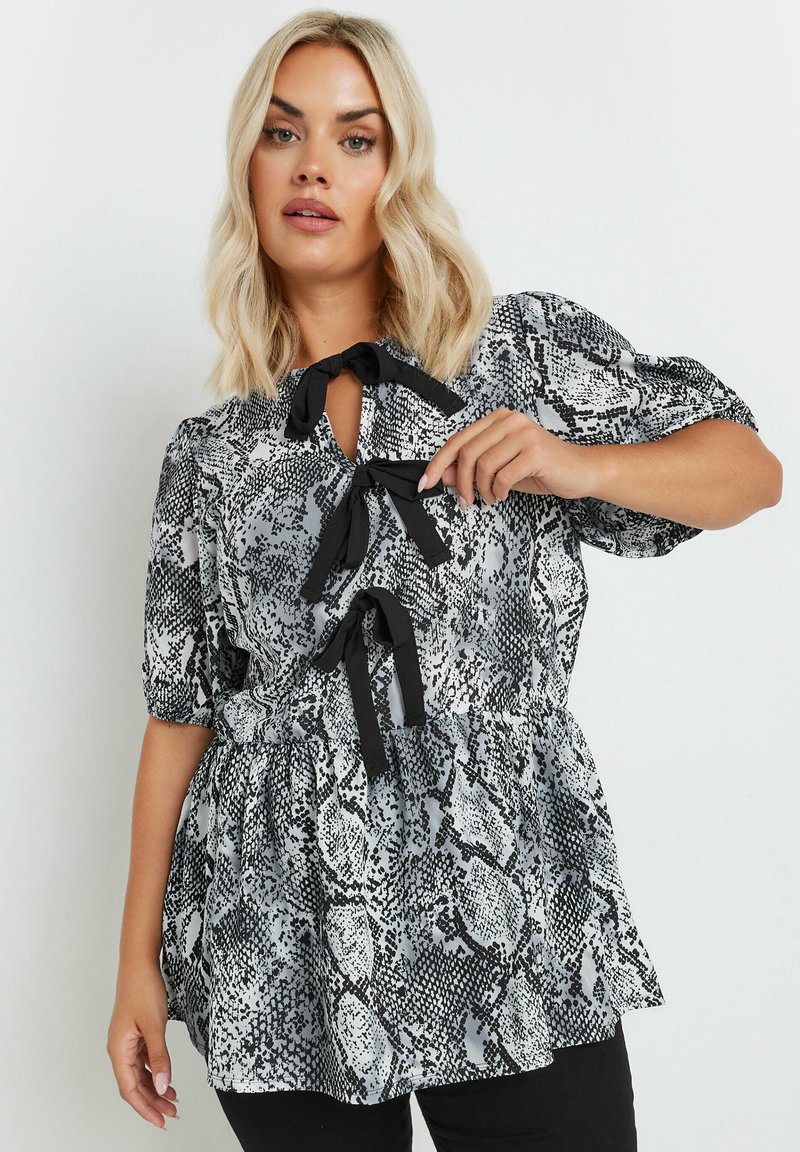 Blusa con estampado de serpiente en blanco y negro, con mangas cortas abullonadas, lazos de tela en el cuello y un dobladillo acampanado. Textura suave, material ligero.