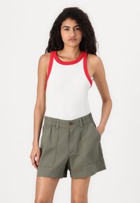 Vit ribbad tank top med röda detaljer, tillsammans med olivgröna shorts med elastisk midja och sidofickor.