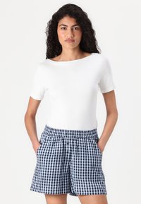 Haut blanc à manches courtes associé à un short à carreaux vichy bleu et blanc. Le short présente une taille élastique et des poches latérales.