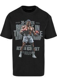 Crna majica s printom boksača s kovrčavnom kosom i crvenim rukavicama, tekst kaže "Rumble in the Jungle" i detalji o događaju.