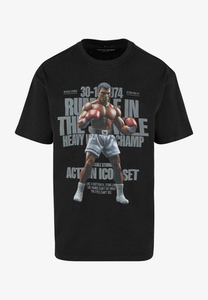 Crna majica s printom boksača s kovrčavnom kosom i crvenim rukavicama, tekst kaže "Rumble in the Jungle" i detalji o događaju.