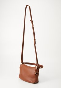 Geantă mică din piele maro, tip crossbody, cu curea ajustabilă și accesorii de culoare aurie, expusă pe un fundal alb.
