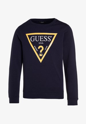 Sweatshirt bleu marine à manches longues, arborant un design de logo triangulaire jaune avec "GUESS U.S.A." et un point d'interrogation au centre.