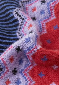 Wielokolorowa dziana tkanina z geometrycznymi wzorami w kolorze fioletowym, czerwonym i niebieskim. Miękka struktura z poziomymi i zygzakowymi paskami.