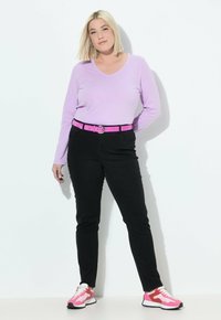 Top de manga larga en color púrpura claro con escote en V, jeans negros con cinturón y zapatillas rosas y blancas con acentos rojos. Diseño simple y forma ajustada.