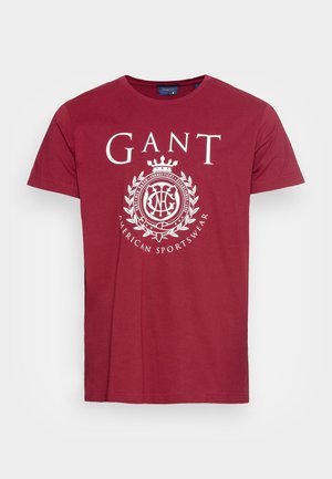 Bordowa bawełniana koszulka z krótkim rękawem posiada białe logo i wzór korony na środku, okrągły dekolt i standardowy krój.