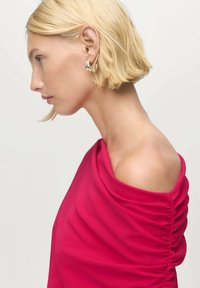 Blusa ceñida, de hombros descubiertos, en tejido rosa vibrante con caída suave y detalles fruncidos a lo largo del lateral. Textura lisa y diseño ceñido al cuerpo.