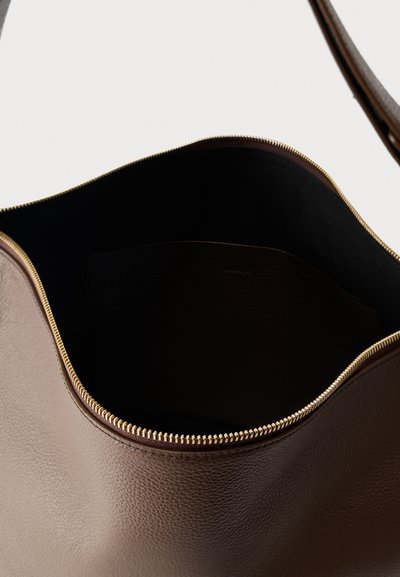 Sac à main en cuir marron avec une fermeture éclair dorée partiellement ouverte, laissant voir un intérieur sombre et une bandoulière.