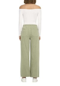 Pantalons larges vert clair avec un taille élastique, dotés de deux poches arrière et d'une texture douce, associés à un haut blanc à épaules dénudées.