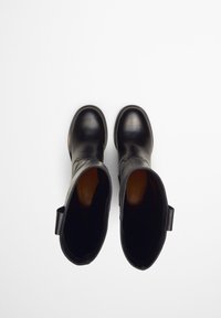 Schwarze Lederknöchelstiefel mit glatter Oberfläche, runder Spitze und niedrigem Absatz. Verfügt über Zuglaschen für ein einfaches Anziehen. Innenfarbe ist beige.