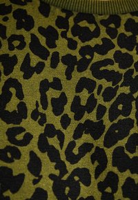 Maglione verde con un motivo leopardato nero caratterizzato da forme e dimensioni variabili. Tessuto morbido e colletto a coste.
