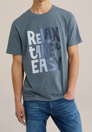 Luźna koszulka z okrągłym dekoltem w kolorze slate blue z bawełny, z graficznym napisem „RELAX TAKE IT EASY” w różnych odcieniach niebieskiego i białym.