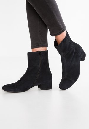 Bottines en daim noir avec un bout carré et un petit talon bloc. Elles sont dotées d'une fermeture éclair extérieure sur un côté et d'une texture lisse.