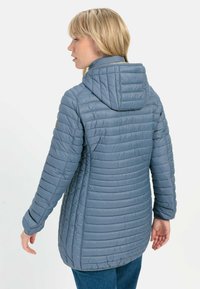 Grijze geïsoleerde jas met een capuchon, voorzien van een gewatteerde textuur en verticale strepen. De achterkant heeft een relaxed fit en subtiele hardwaredetails.