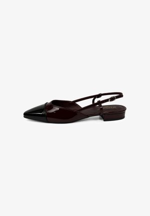 Chaussure plate à bout pointu avec embout noir brillant, corps en cuir verni marron foncé et bride arrière réglable.