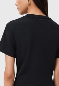 T-shirt nera a maniche corte con collo rotondo, realizzata in cotone morbido e con un'etichetta logo discreta sul retro del collo.