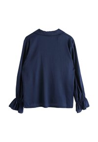 Mörkblå blus med långa, rynkade ärmar och krage. Slät textur och figurnära passform med volangdetaljer i elastisk mudd vid ärmsluten.