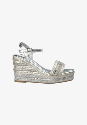 Sandal con tacco a cuneo in metallo argentato, con dettagli in juta intrecciata, cinturino alla caviglia regolabile e ampia fascia frontale con accenti decorativi orizzontali.