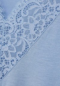 Hellblaues Gewebe mit Spitze entlang der Kante; glatte Textur mit floralen Mustern, die die Weichheit des Kleidungsstücks unterstreichen.