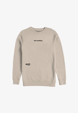 Sudadera beige de manga larga con texto "STAY SURREAL" centrado en el pecho y logo "apoh London" cerca del dobladillo izquierdo.