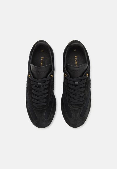 Black suede sneakers with smooth black leather accents, featuring black laces, gold eyelets, and a textured sole. Elegant minimalist design.