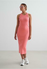 Rochie midi ajustată, cu dungi, în nuanța roz aprins. Design fără mâneci și decolteu rotund. Purtați cu teneși albi și ochelari de soare cu tentă.