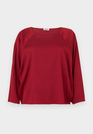 Haut rouge à manches longues avec un col rond, fabriqué en tissu doux ; présente des manches raglan et une coupe décontractée, une texture lisse, sans motifs visibles.