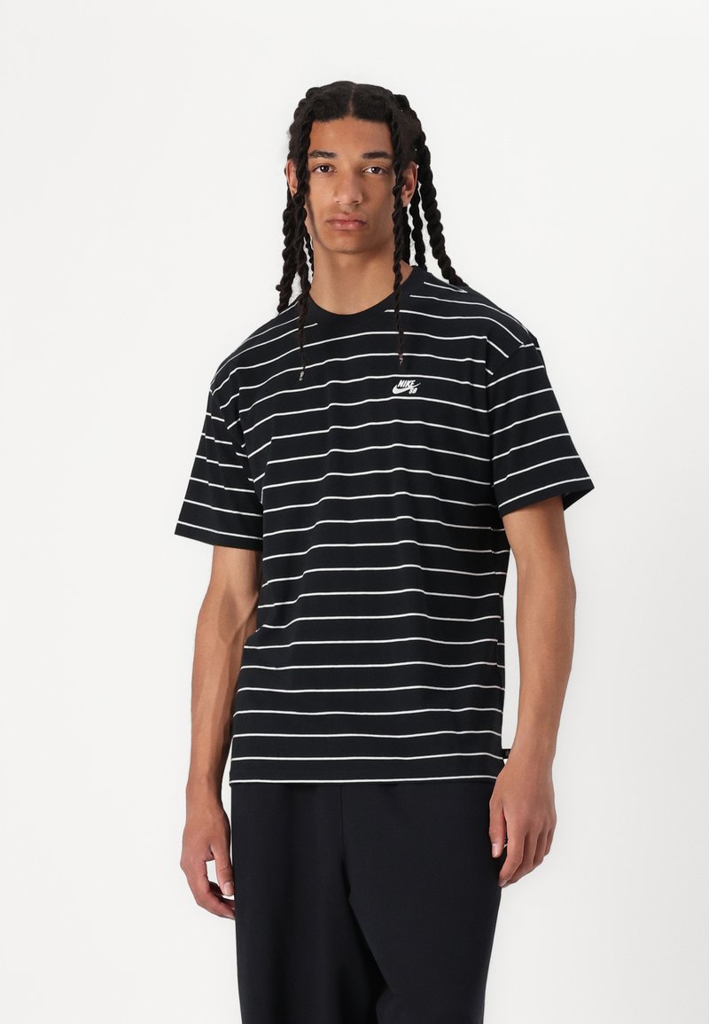 Schwarz-weißer gestreifter T-Shirt mit kurzen Ärmeln, ausgestattet mit einem kleinen weißen Nike-Logo auf der Brust, aus weichem Baumwollmaterial gefertigt.