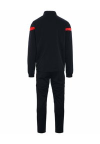 Survêtement noir avec col haut, arborant des accents rouges sur les épaules. Le tissu semble lisse avec des poignets et un pantalon ajustés.