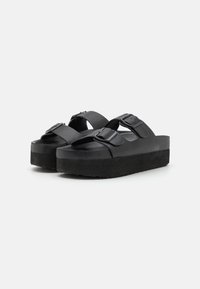 Black platform sandals with two wide straps and square buckles. Featuring a textured footbed and a thick, solid black sole.