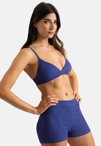 Ce bralette en ribbed violet est doté de fines bretelles réglables ; associé à un shorty ribbed assorti, il offre un look ajusté et sans couture.