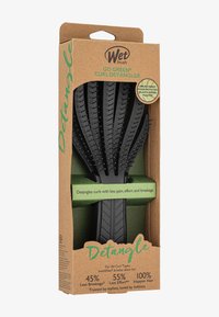 Spazzola districante a forma di curling di colore nero con setole IntelliFlex. Imballata in cartone ecologico con accenti verdi e dettagli del prodotto stampati.