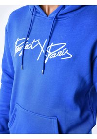 Felpa blu con tasca frontale, cordini e testo bianco "Project X Paris" sul petto.