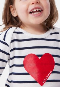 Βαμβακερό πουκάμισο με μακριά μανίκια σε οριζόντιες ρίγες ναυτικού μπλε και λευκού, με μεγάλο κόκκινο γραφικό καρδιάς και κείμενο "petit bateau".