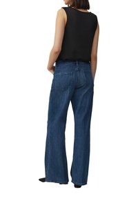 Jean en denim bleu foncé à jambes larges et taille mi-haute. Comprend deux poches arrière et une finition soignée à l'ourlet. Tissu texturé, style décontracté.