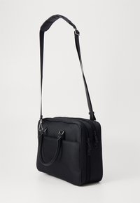 Borsa a tracolla nera con superficie texture, doppie cerniere, tasca frontale e tracolla staccabile. Design compatto rettangolare.