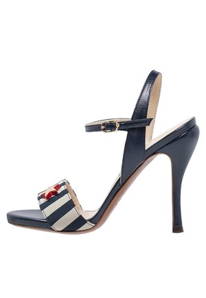 Granatowa sandał na wysokim obcasie o błyszczącej powierzchni, z paskiem z materiału w paski i czerwonym akcentem w kształcie gwiazdy. Regulowany pasek na kostkę dla lepszego dopasowania.