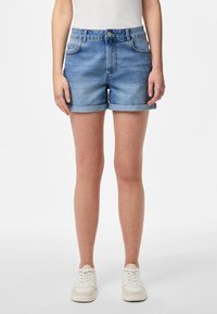 Gaiši zili džinsi šorti ar ruļļu apakšējo malu, priekšējām kabatām un klasisku pogu un rāvējslēdzēja aizdari, izgatavoti no mīksta, teksturēta auduma.