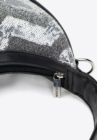 Zwarte schoudertas met een zilveren decoratie van pailletten, ronde vorm, ritssluiting en logoaccent op het beslag. Textuur op het oppervlak voegt visuele interesse toe.