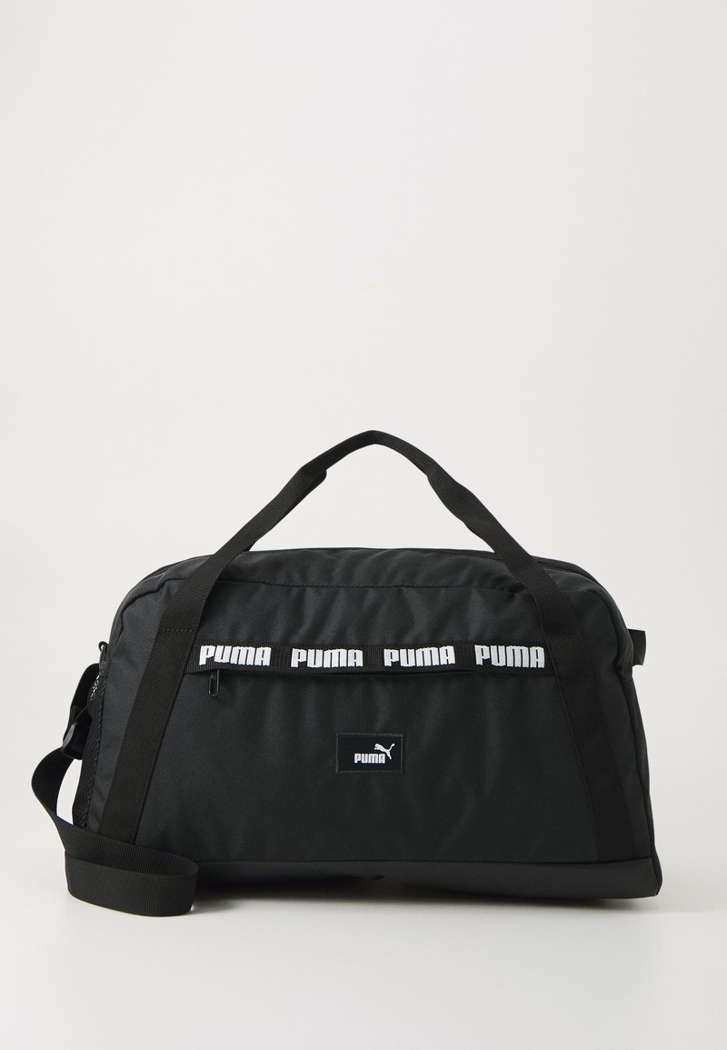 Svart duffel bag laget av nylon, med en glidelåslomme, håndtak og en justerbar stropp. Utsmykket med hvit Puma-logo.