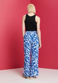 Svart linne som kombineras med blå och vita blommiga vida byxor, med resårmidja och avslappnad passform. Slät tygstruktur.