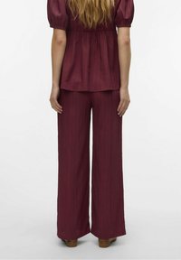 Burgundský dvoudílný outfit s rozšířeným lemem, texturovanou tkaninou a krátkými nabíranými rukávy, s volně střiženým topem a kalhotami širokého střihu.
