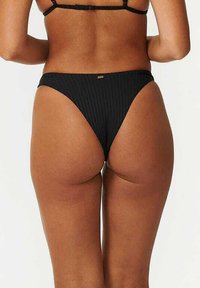 Zwarte geribbelde bikini onderkant met een hoge snit, voorzien van een gladde stoftextuur en minimalistische goudkleurige hardwaredetails.